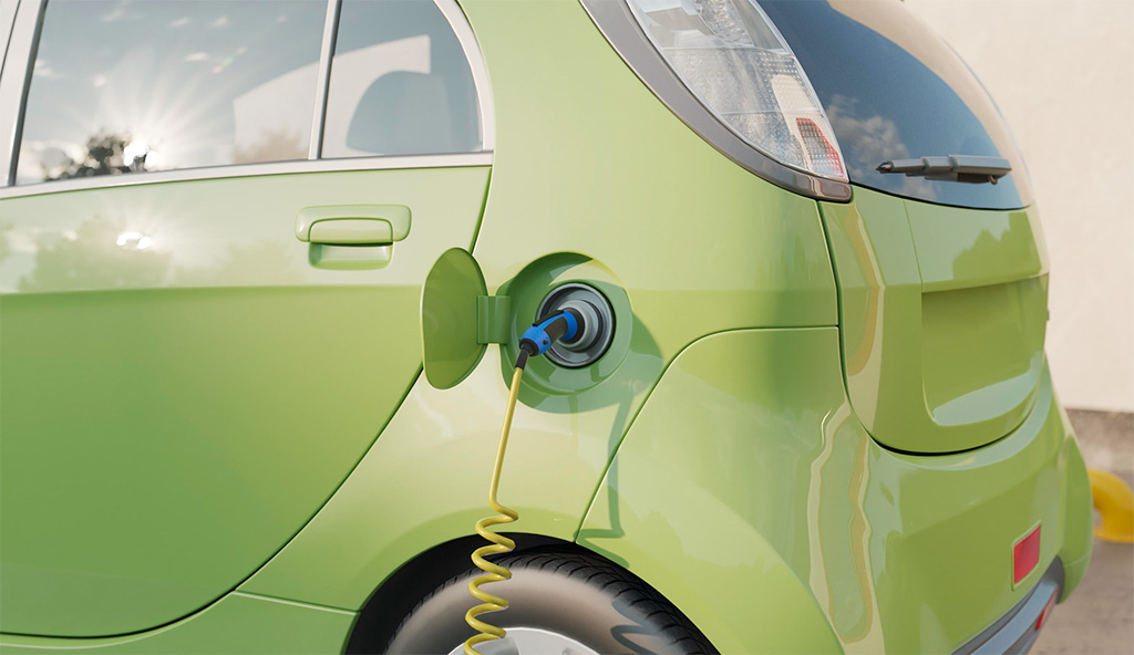 Parte trasera de un vehículo verde kiwi, el cual tiene una manguera conectada en el punto de recarga eléctrica