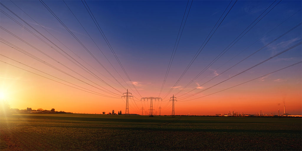 Torres eléctricas con fondo azul oscuro y naranja de atardecer