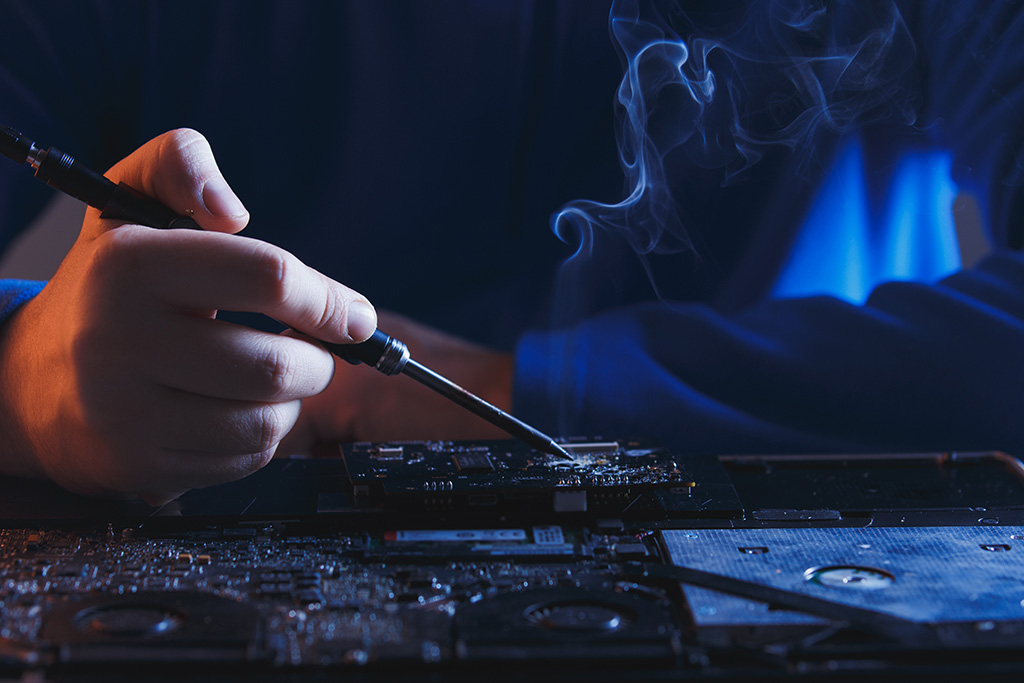 una mano soldando un microchip