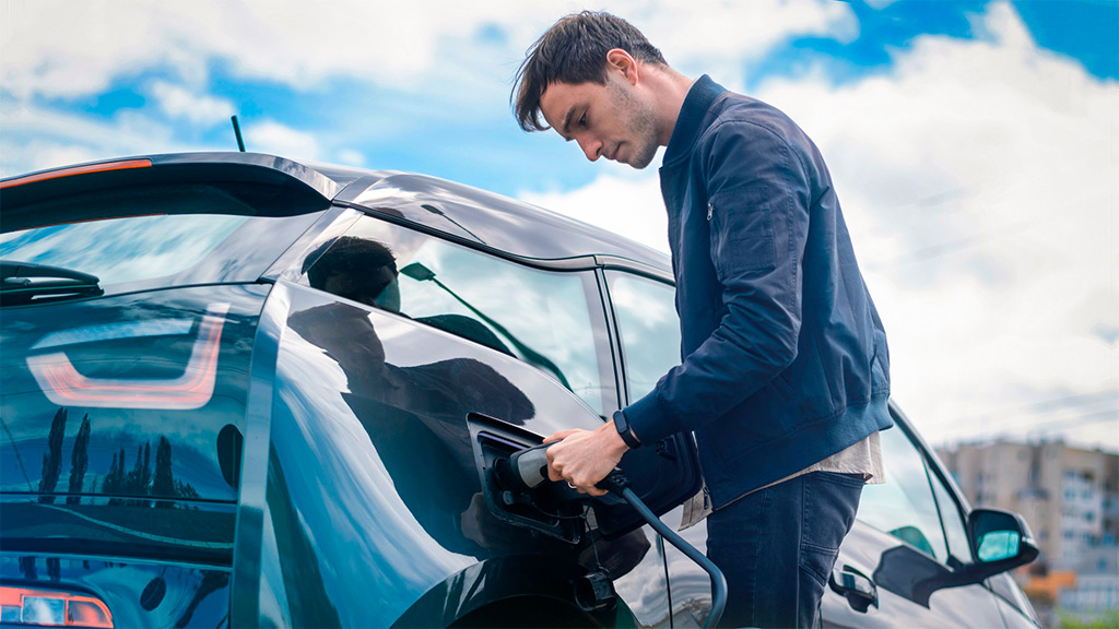 Hombre cargando su coche eléctrico en estación de carga