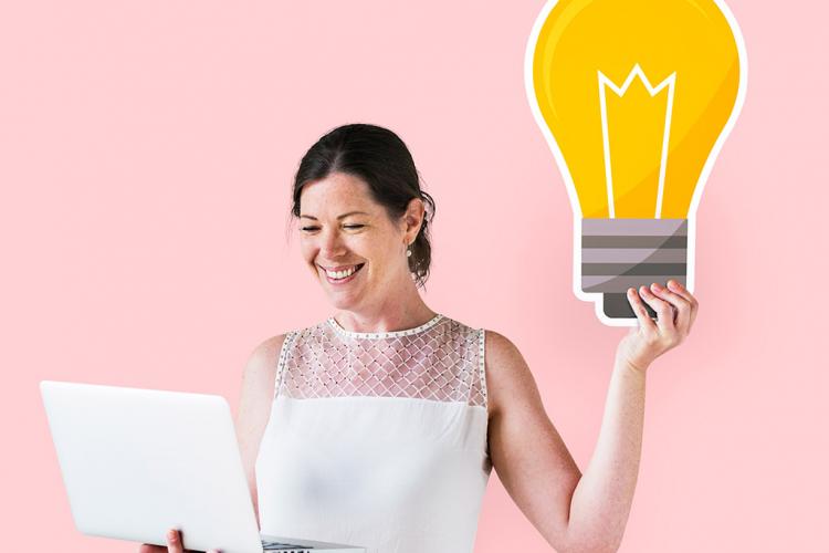 Mujer sosteniendo con la mano derecha un portátil y, con la mano izquierda, una bombilla de cartón.