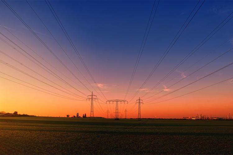 Torres eléctricas con fondo azul oscuro y naranja de atardecer