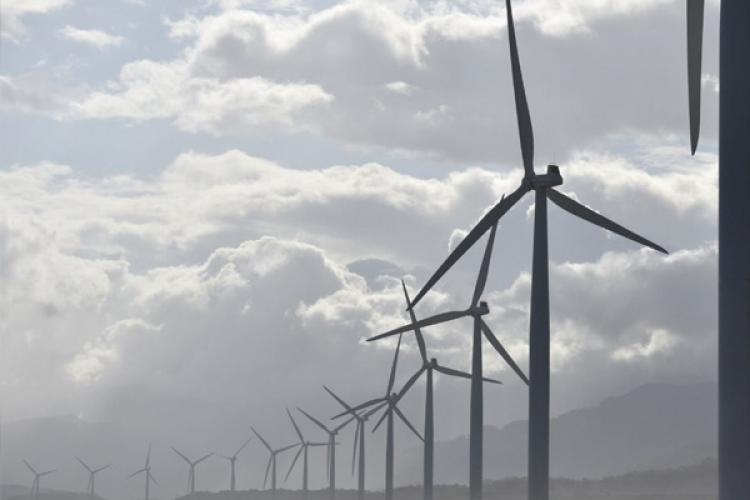 una hilera de molinos de viento sobre un fondo con cielo nuboso