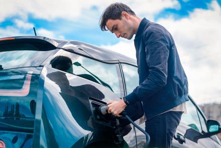 Hombre cargando su coche eléctrico en estación de carga