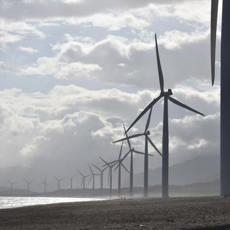 una hilera de molinos de viento sobre un fondo con cielo nuboso